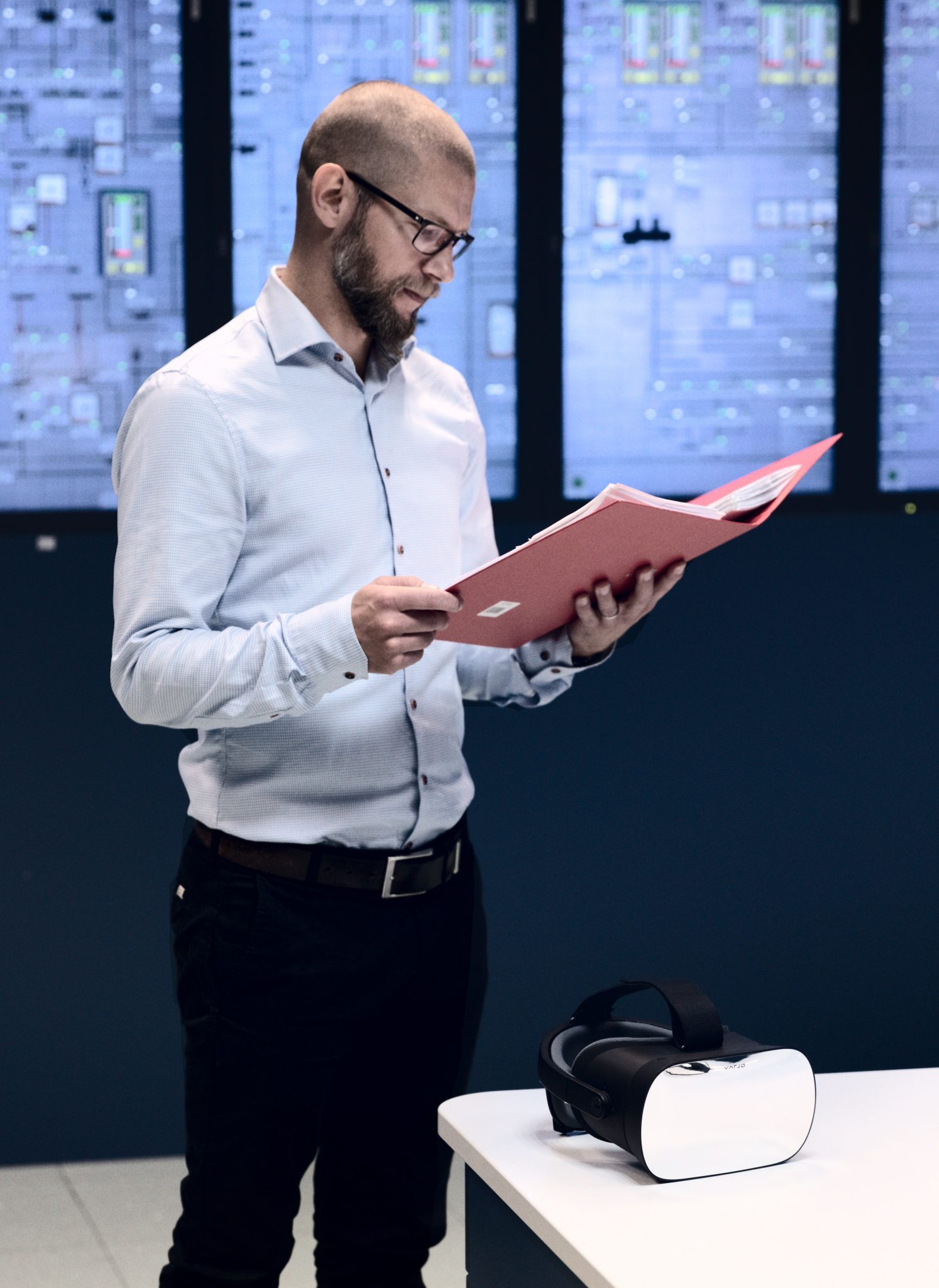 A person standing in front of screens, reading a folder