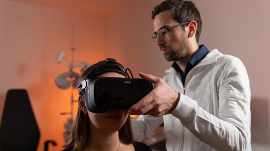 A person fitting a VR headset for another