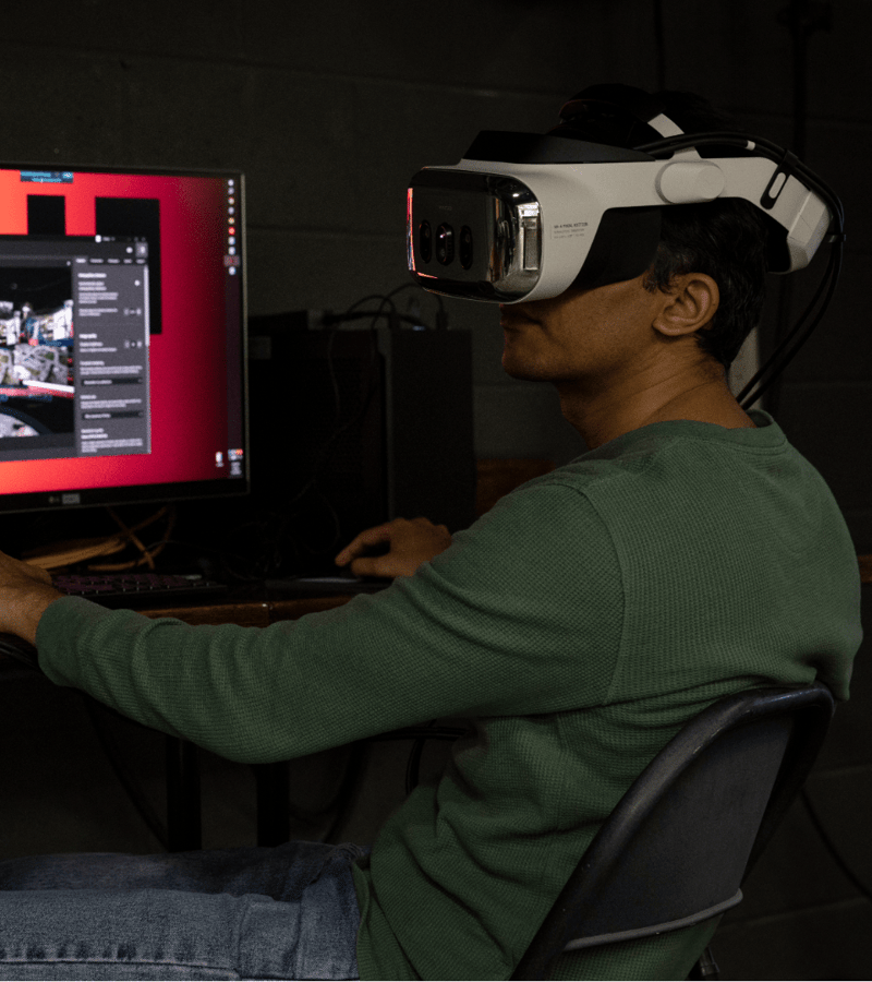 A person wearing a VR headset, sitting in front of a screen