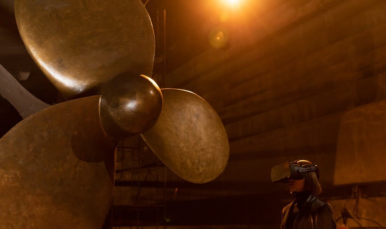 a person wearing a VR headset next to a giant propeller